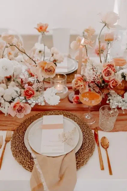 Détail d’une table dressée, fleurs pêche et assiette dorée