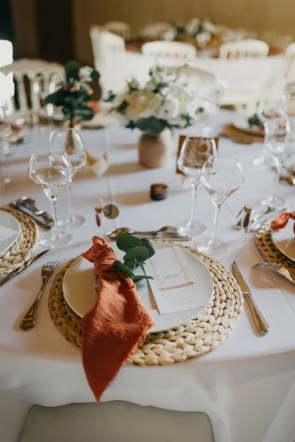 Table ronde dressée, serviette terracotta et sets en osier